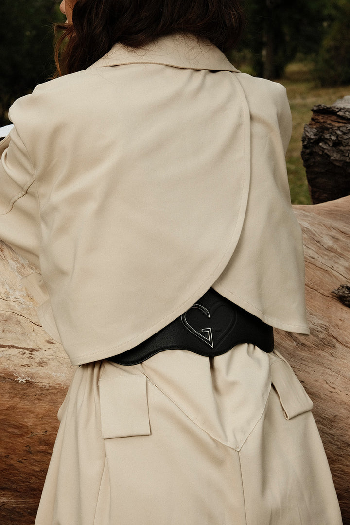 Person wearing a beige trench coat with a blurred natural background