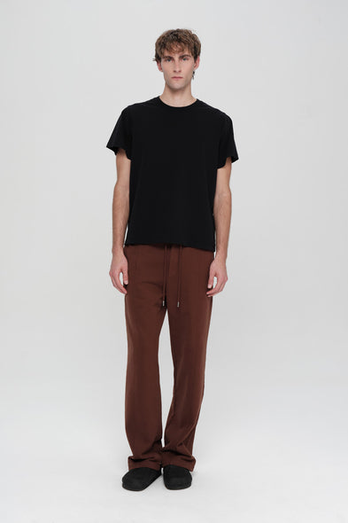 Person wearing a black t-shirt and brown pants on a white background