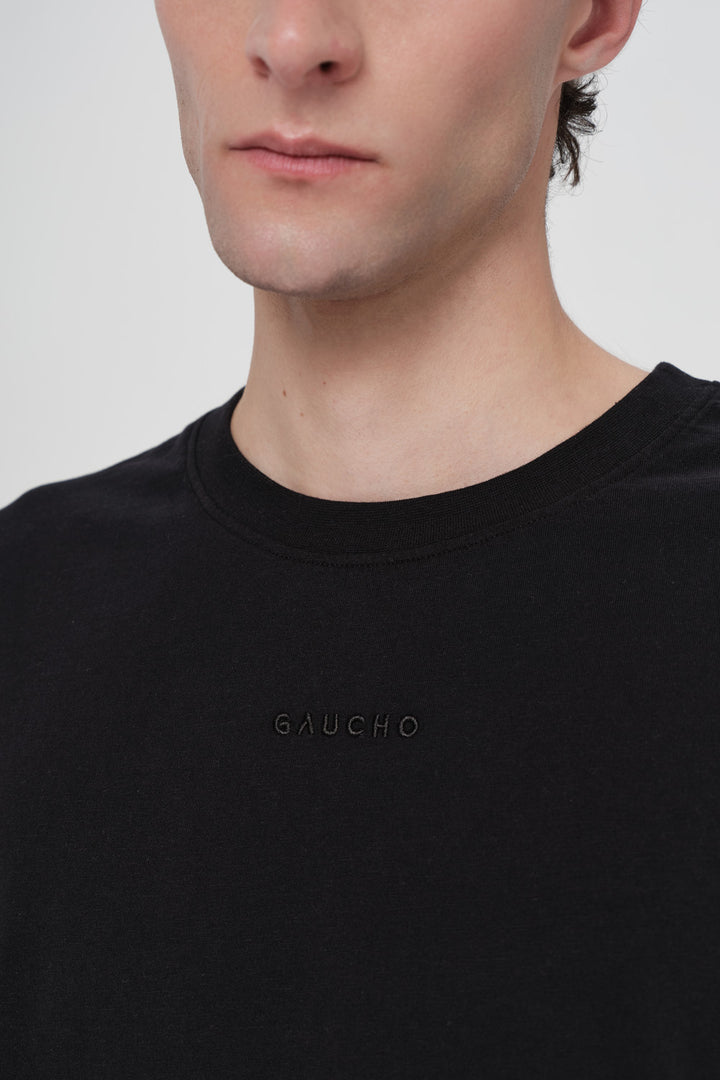 Person wearing a black t-shirt with 'Giucho' branding on a plain background