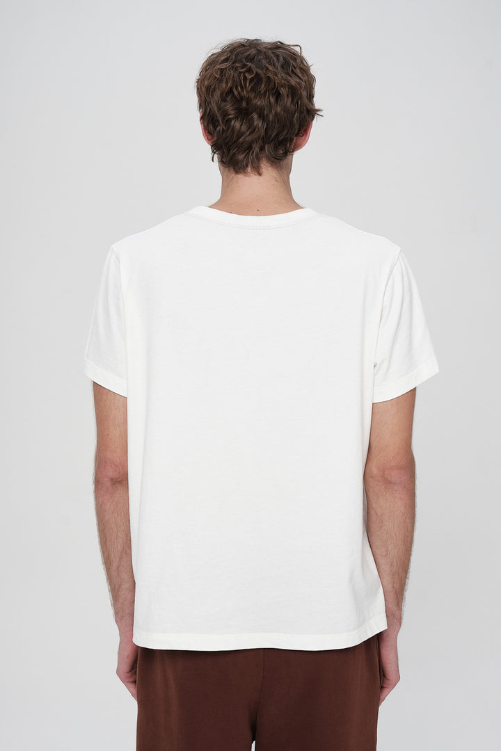 Person wearing a plain white t-shirt on a light gray background