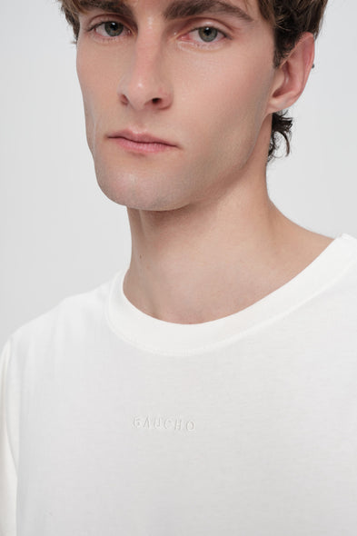 Man wearing a white t-shirt with a brand logo on a light gray background