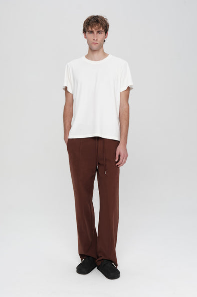 Person wearing a white t-shirt and brown pants on a white background