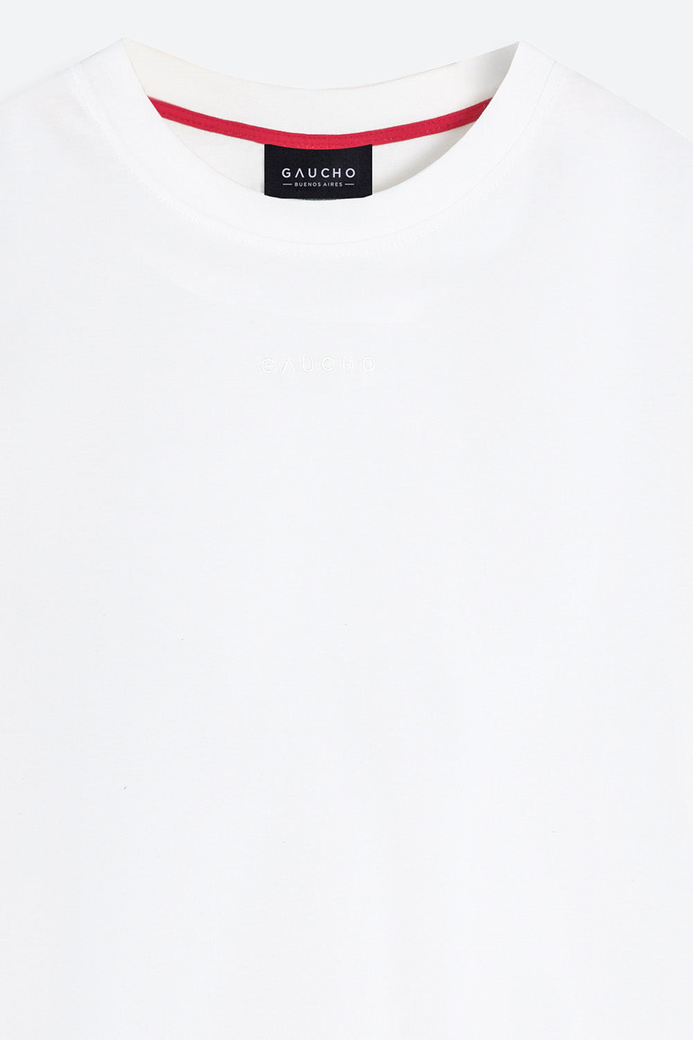 Close-up of a white shirt with red trim and a Gaucho label on a white background