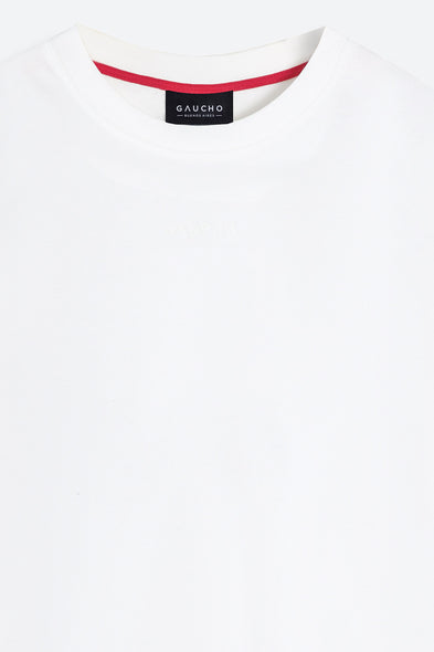 Close-up of a white shirt with red trim and a Gaucho label on a white background