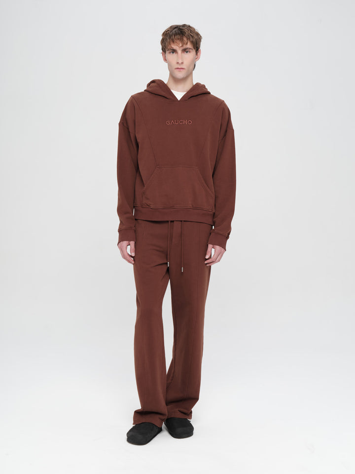 Man wearing a brown hoodie and pants set on a white background