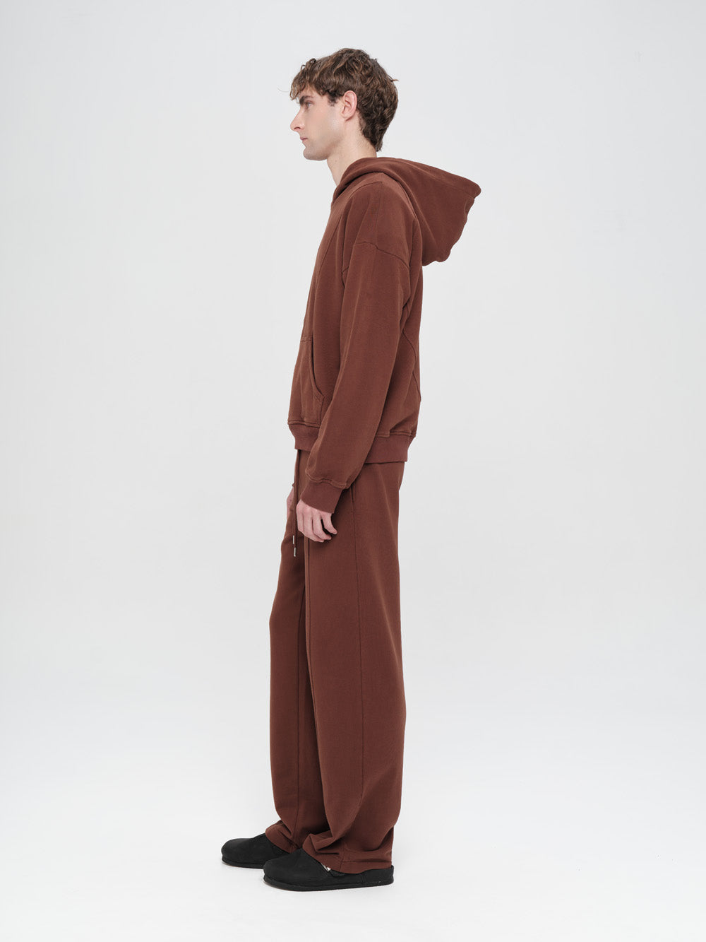 Person wearing a brown onesie against a white background