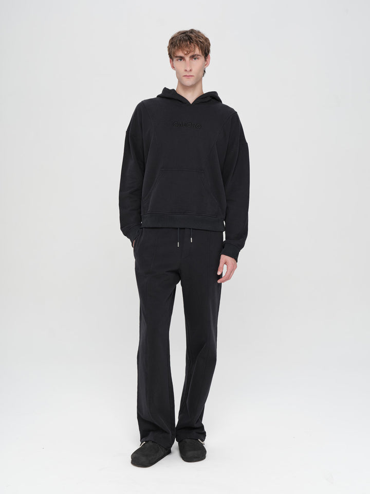 Person wearing a black hoodie and pants on a white background
