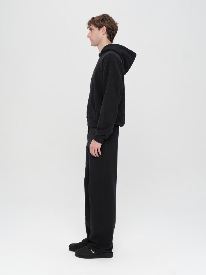 Person wearing a black onesie with a hood on a white background