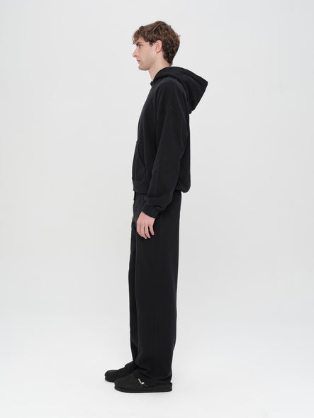 Person wearing a black onesie with a hood on a white background