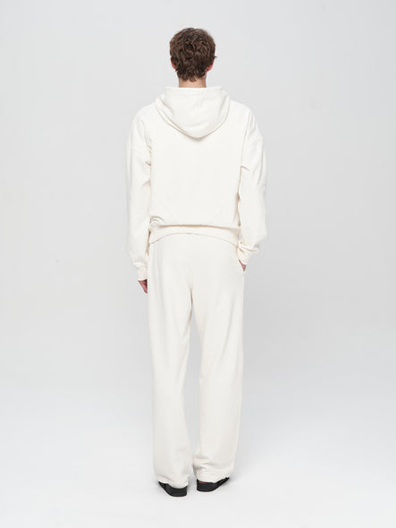 Person wearing a white hoodie and pants on a light gray background