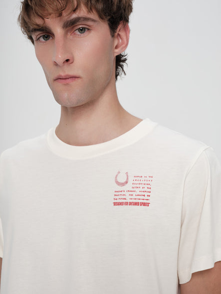 Person wearing a white t-shirt with red text and graphics on a plain background