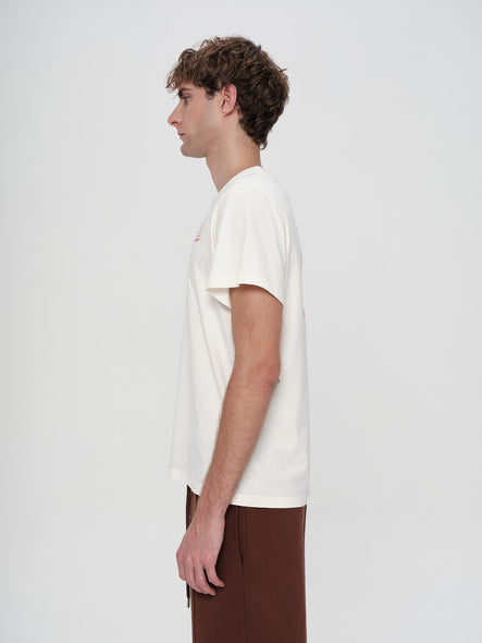 Man wearing a white t-shirt and brown pants on a light gray background