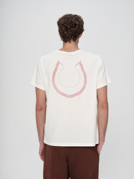Person wearing a white t-shirt with a pink horseshoe design on the back against a plain background