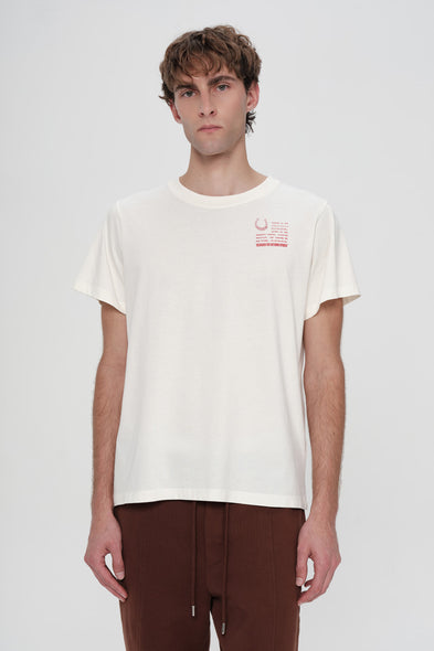 Person wearing a white t-shirt with a small red logo on a plain background