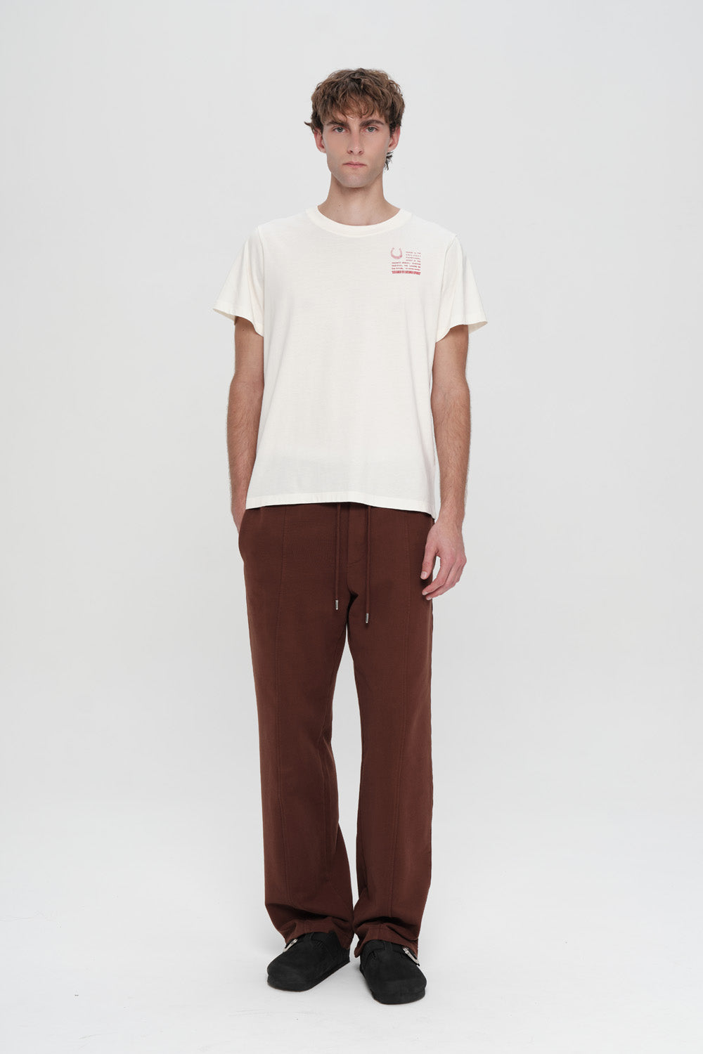 Person wearing a white t-shirt and brown pants on a white background