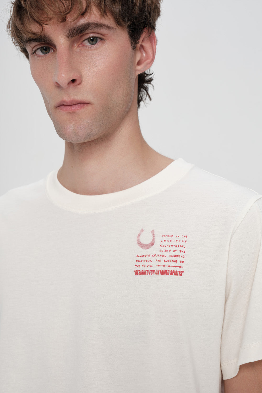 Man wearing a white t-shirt with red text and graphic on a plain background