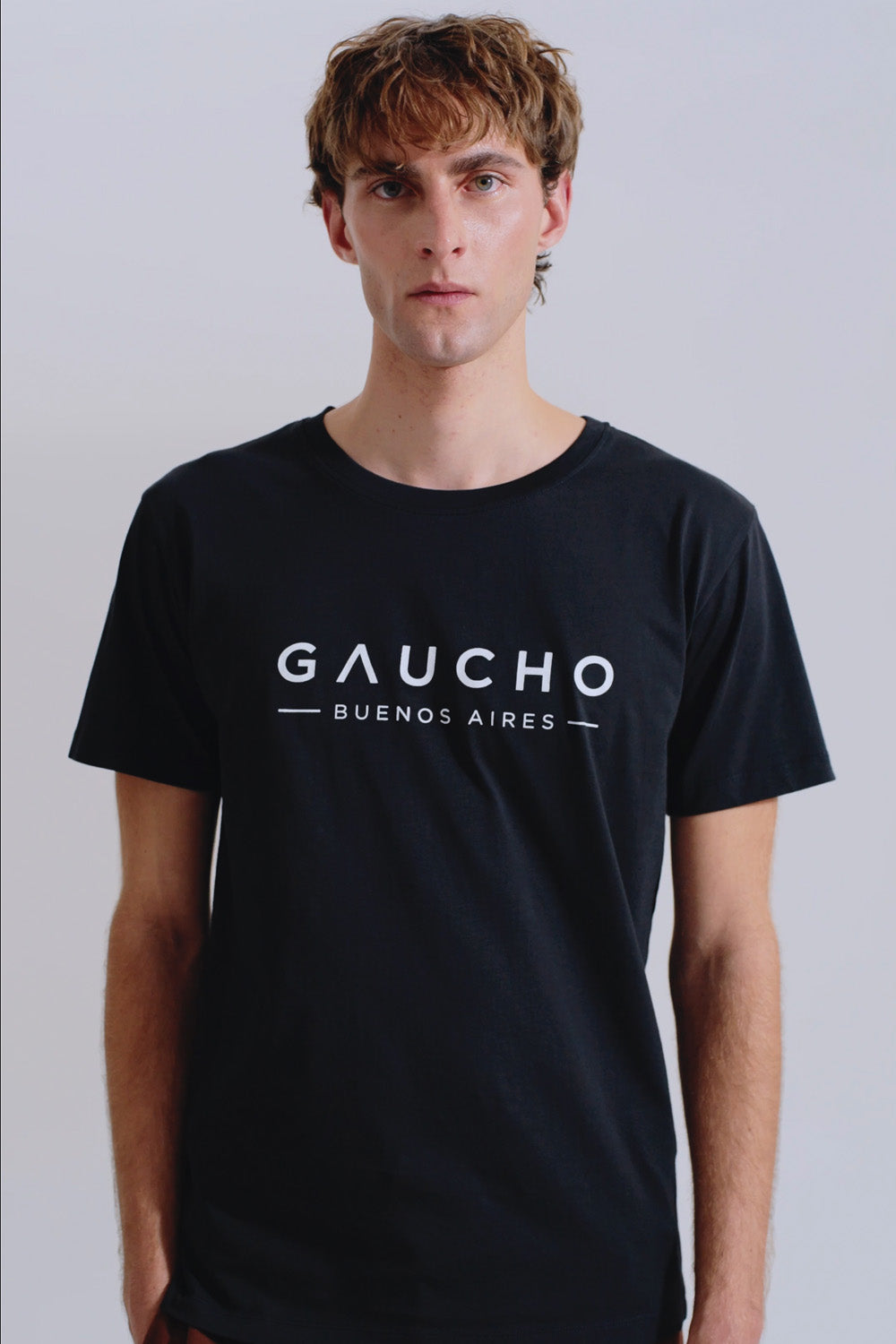 Person wearing a black t-shirt with 'Gaucho Buenos Aires' text on a plain background