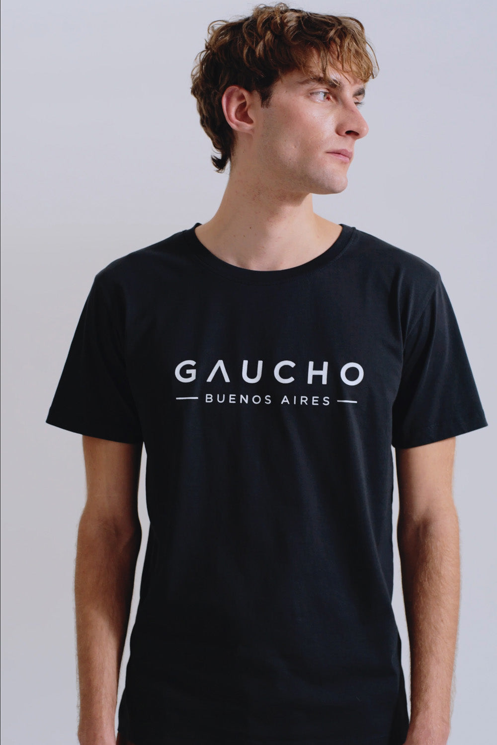 Person wearing a black t-shirt with 'Gaucho Buenos Aires' text on a plain background
