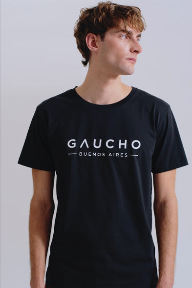Person wearing a black t-shirt with 'Gaucho Buenos Aires' text on a plain background