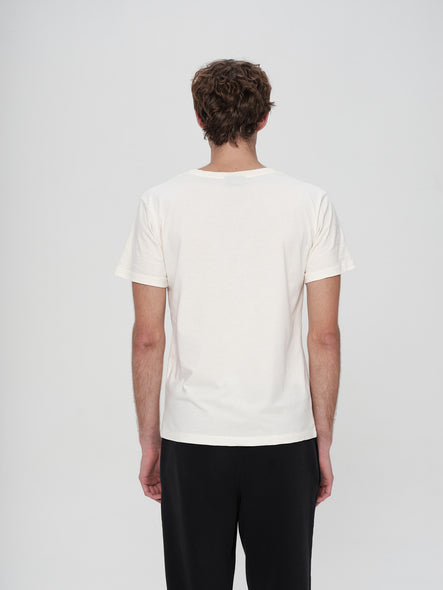 Person wearing a plain white t-shirt and black pants on a light gray background