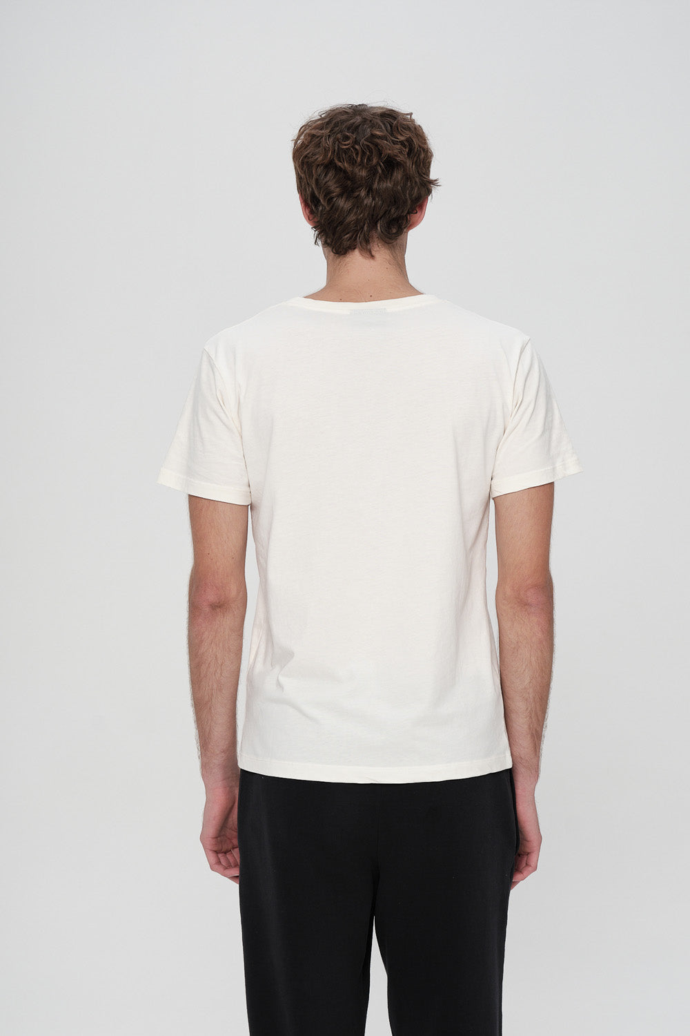 Person wearing a plain white t-shirt on a light gray background