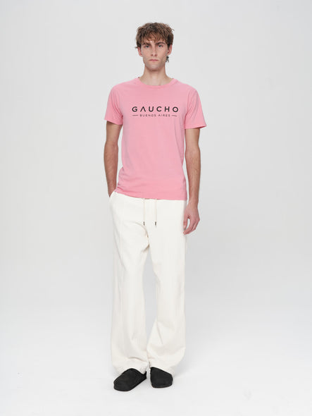 Person wearing a pink t-shirt with 'Gaucho' logo on a white background