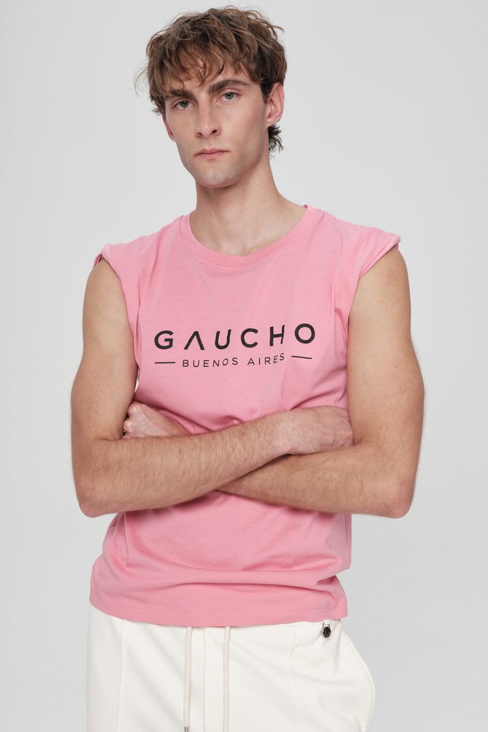 Person wearing a pink sleeveless shirt with 'Gaucho Buenos Aires' text on a plain background