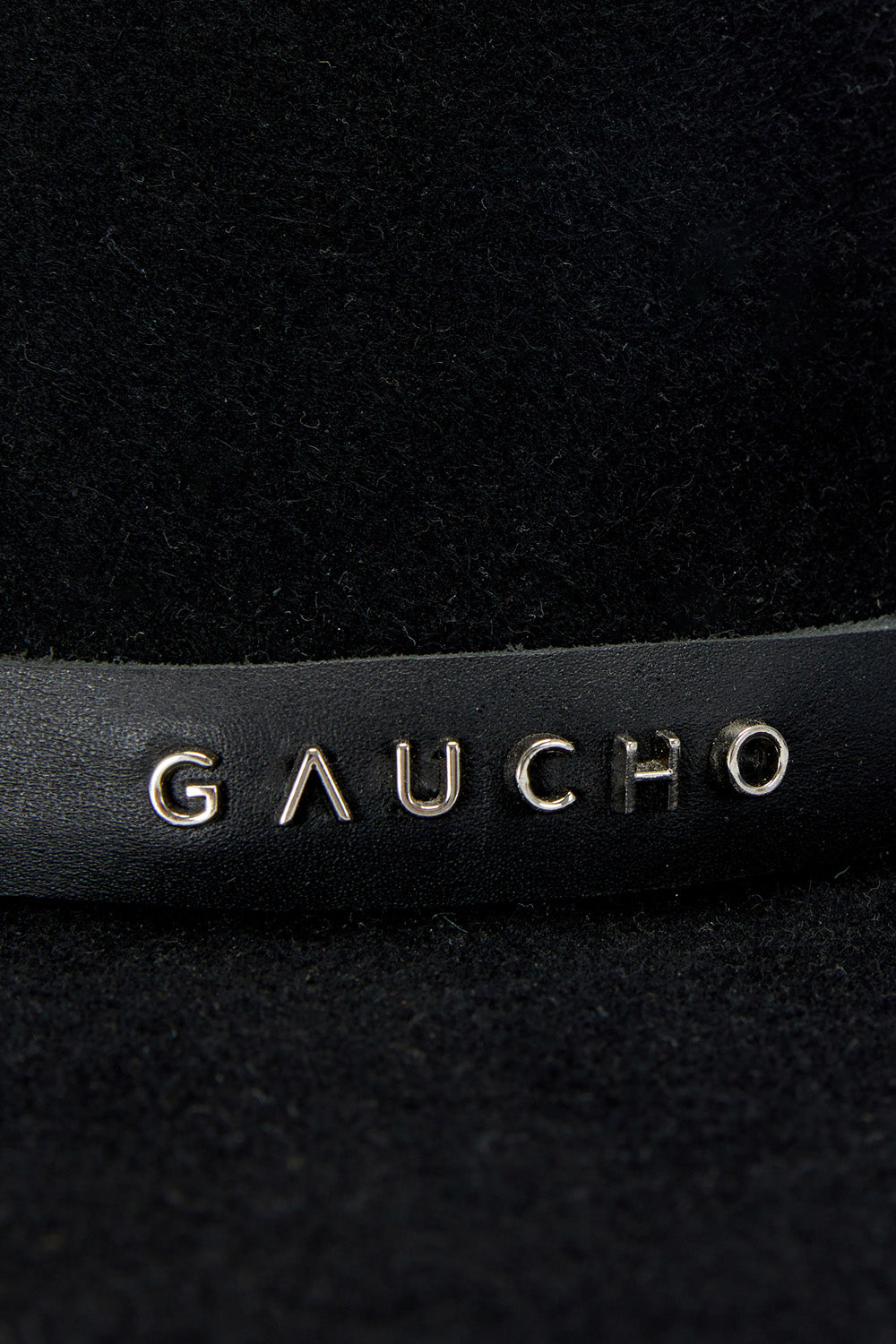 Close-up of a black leather product with 'Gaucho' branding.