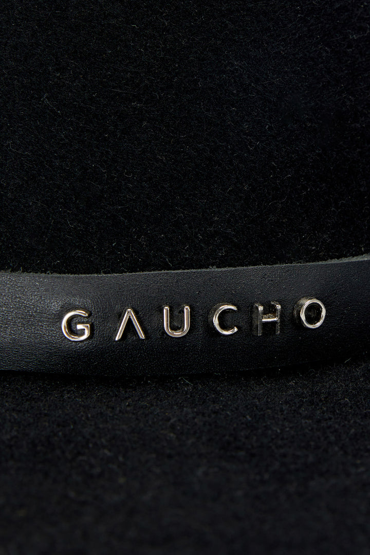 Close-up of a black leather product with 'Gaucho' branding.