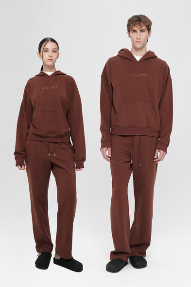 Two people wearing matching brown hoodies and pants on a white background