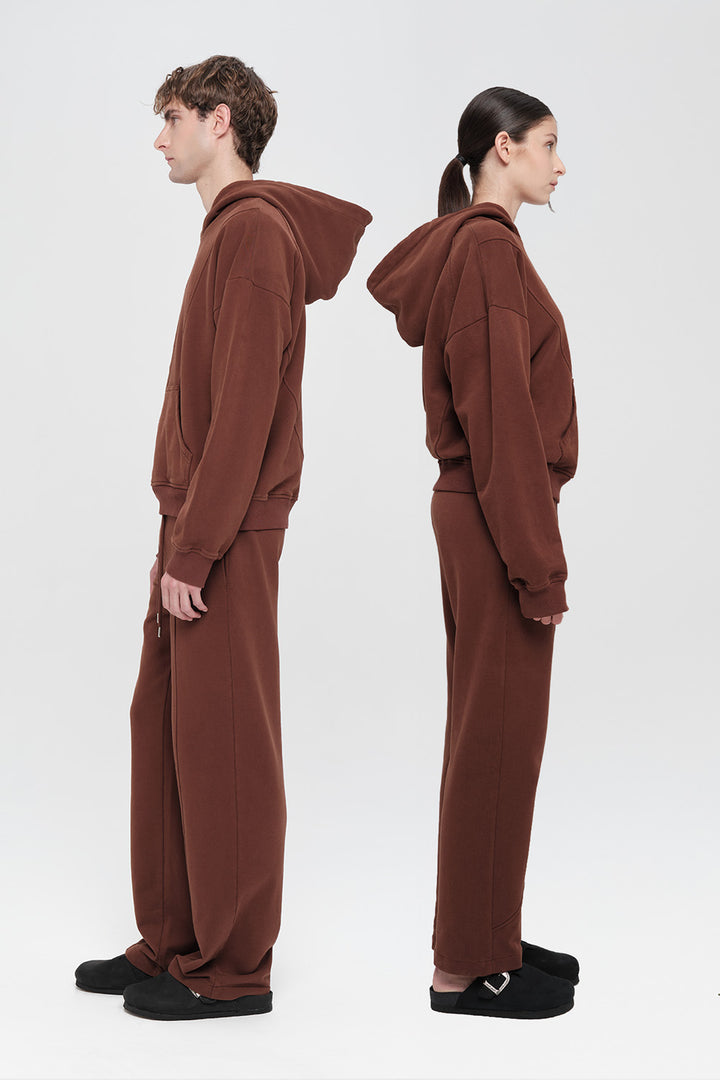 Two people wearing brown hoodies and pants on a white background