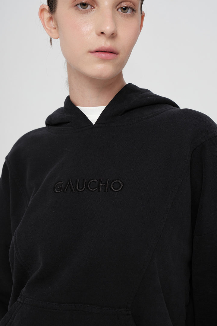 Person wearing a black hoodie with 'Gaucho' branding on a white background
