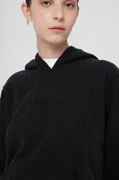 Person wearing a black hoodie with 'Gaucho' branding on a white background