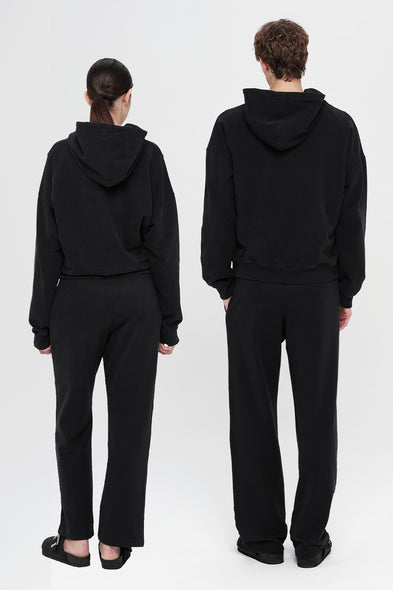 Two people wearing black hoodies and pants from different angles on a white background