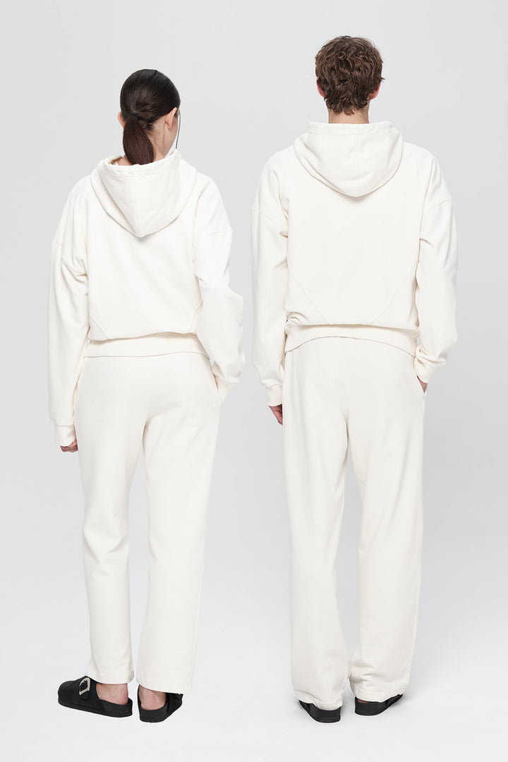 Two people wearing white hoodies and pants standing back-to-back on a plain background