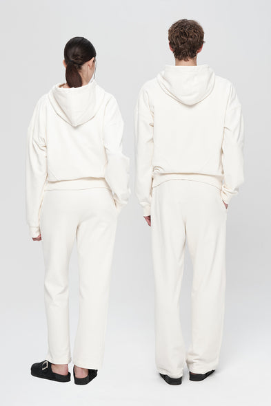 Two people wearing white hoodies and pants standing back-to-back on a plain background