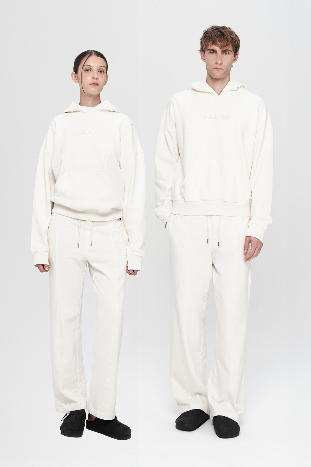 Two people wearing matching white outfits on a plain background