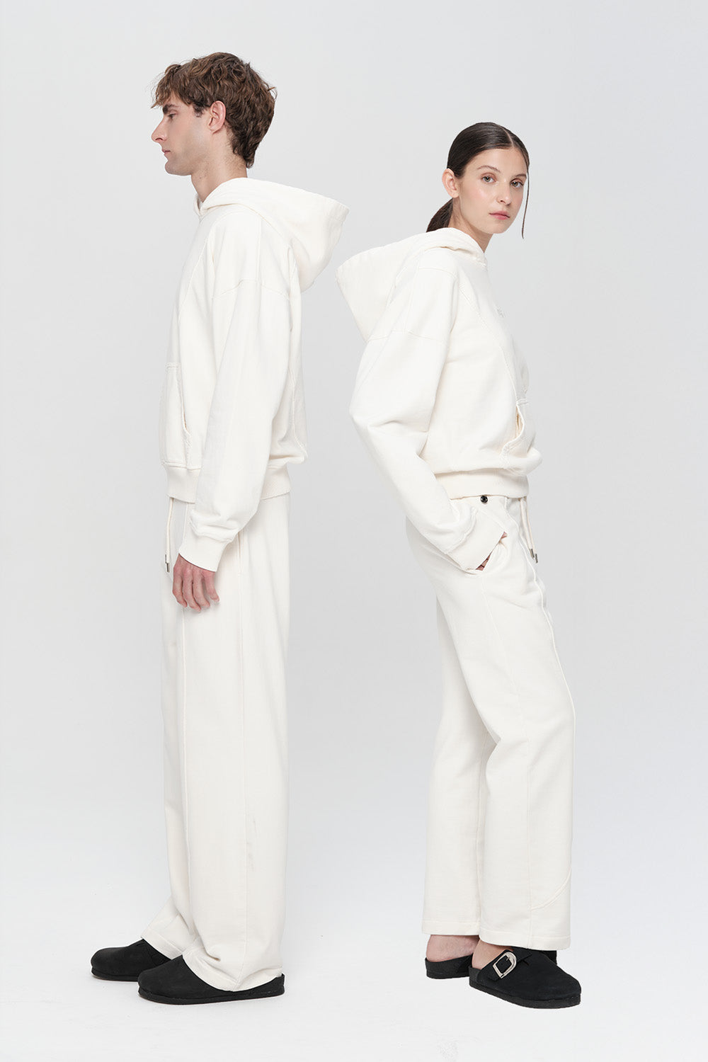 Two people wearing white outfits on a plain background