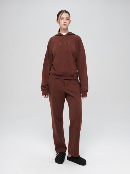 Person wearing a brown tracksuit with a visible brand logo on a white background