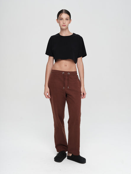 Person wearing a black crop top and brown pants on a white background