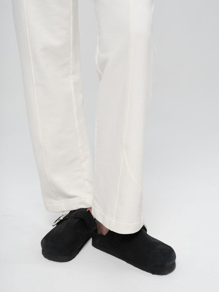 Person wearing black shoes and white pants on a light gray background