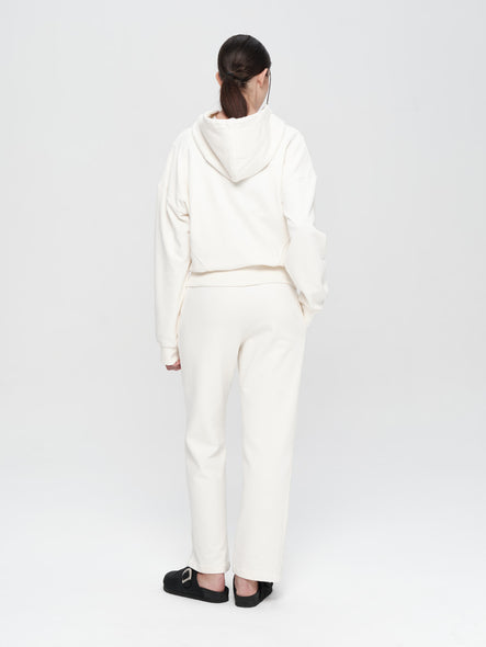 Person wearing a white hoodie and pants on a plain background