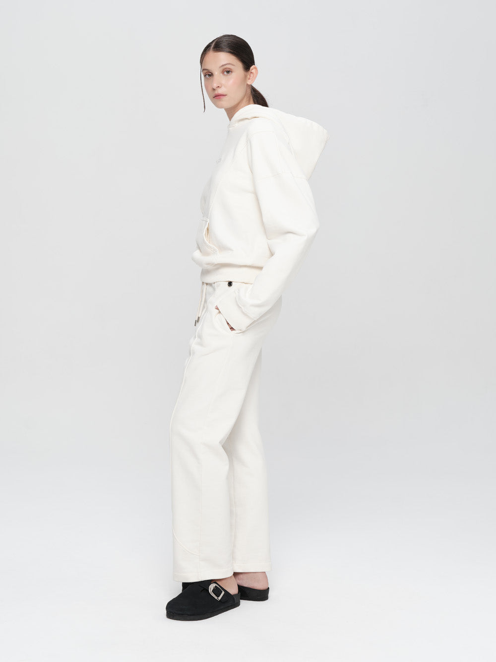 Person wearing a white outfit with black shoes on a light gray background