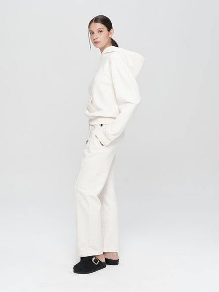 Person wearing a white outfit with black shoes on a light gray background