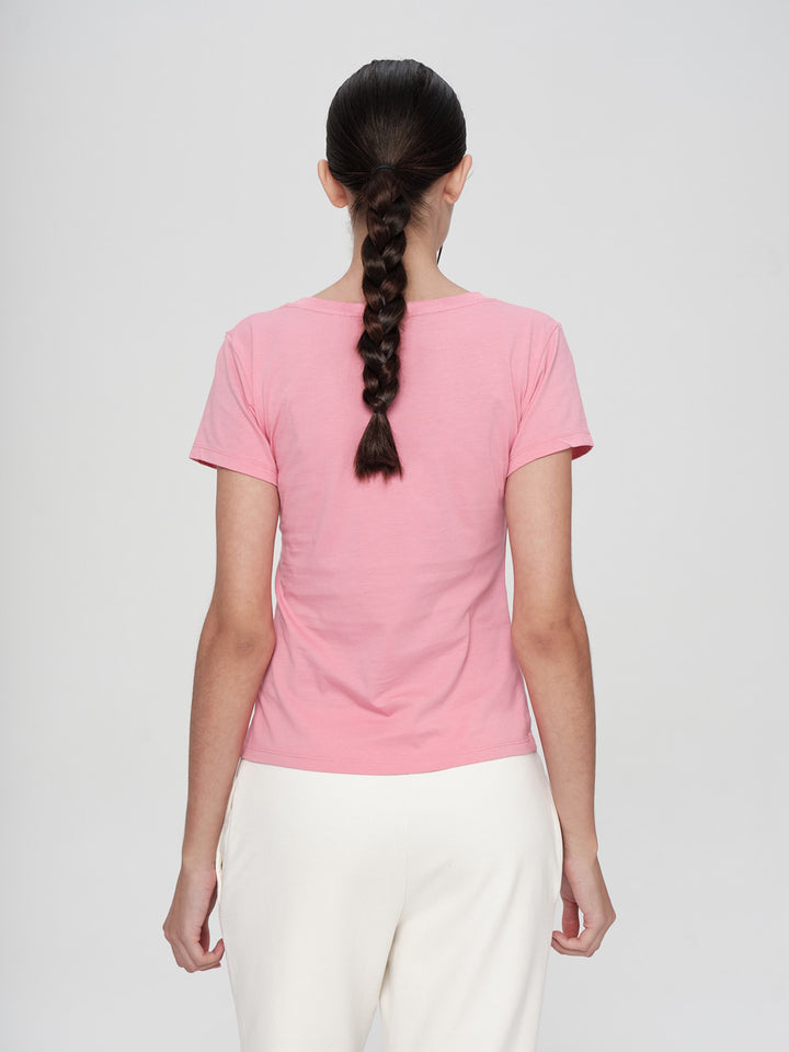 Person wearing a pink t-shirt and white pants on a plain background
