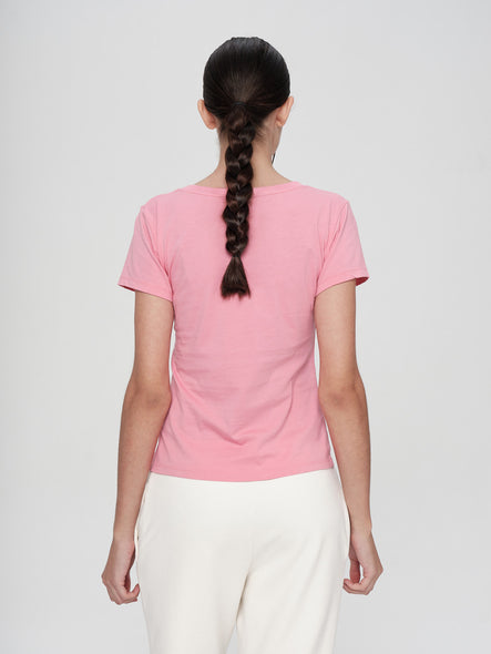 Person wearing a pink t-shirt and white pants on a plain background