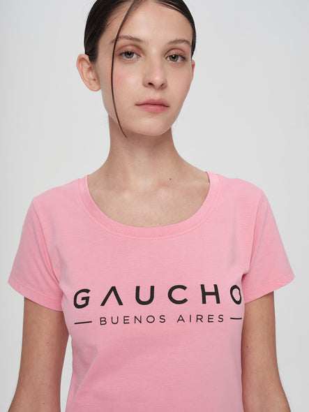 Person wearing a pink t-shirt with 'Gaucho Buenos Aires' text on a plain background