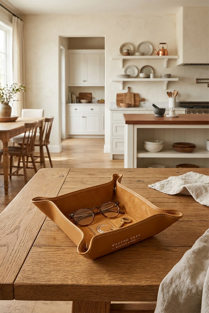 Brown leather tray with sunglasses on a wooden table in a kitchen.