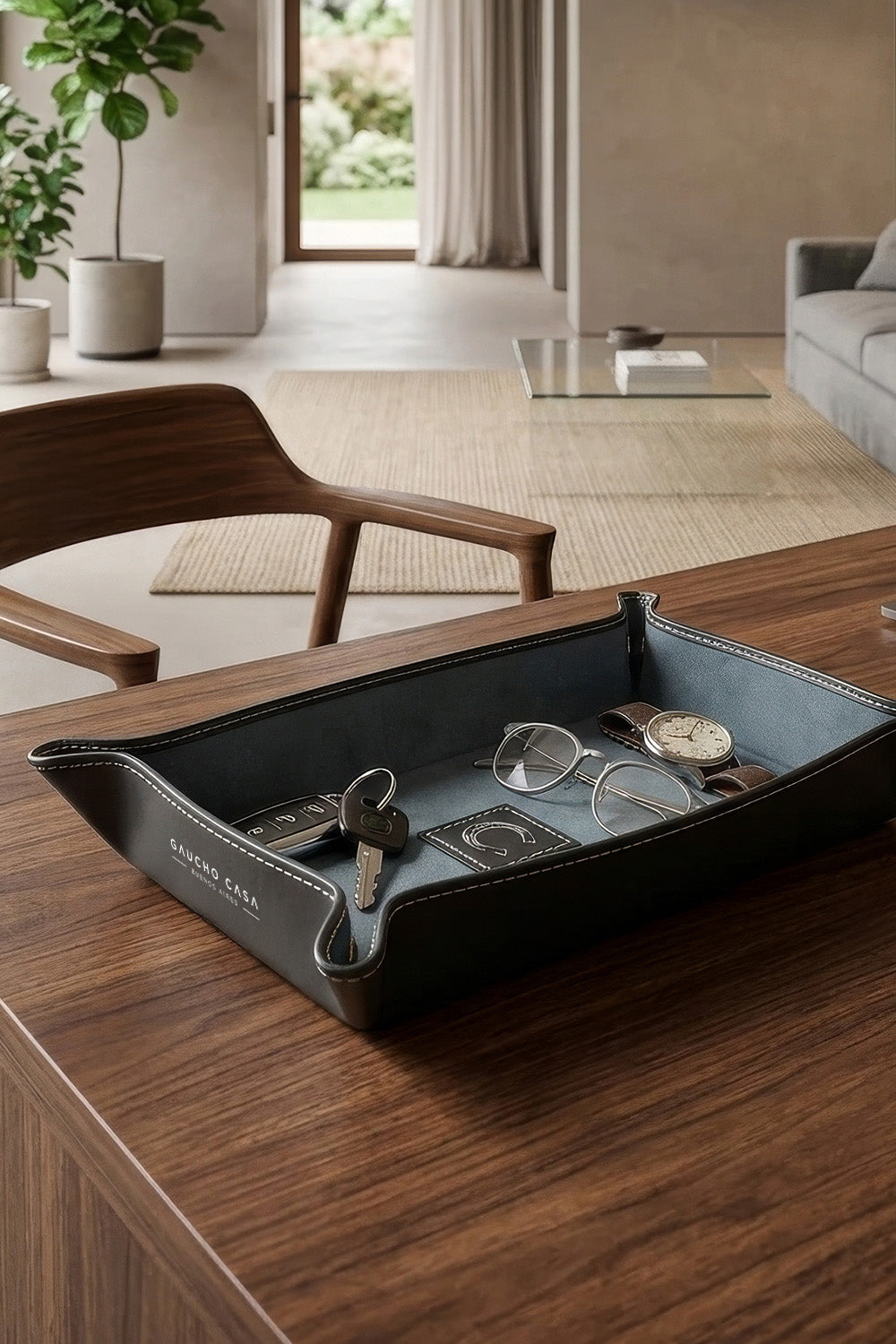 Black tray with accessories on a wooden surface in a modern living room.