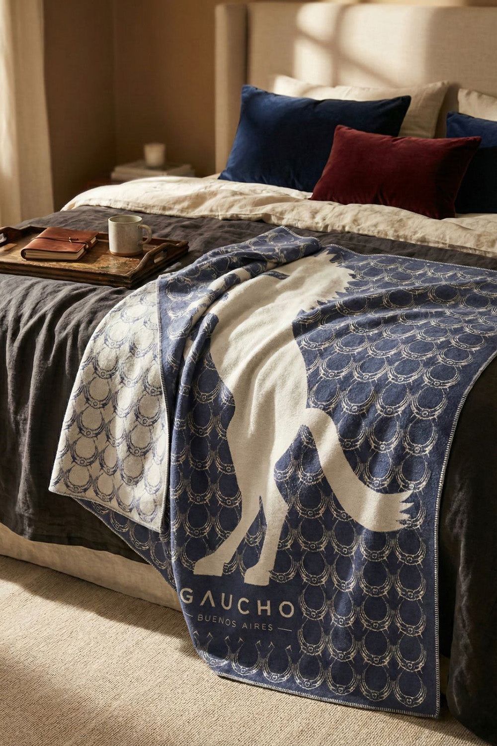 Bed with a Gaucho blanket draped over it, featuring a logo and text.